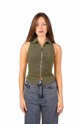 Woman wearing a green sleeveless top with a zipper and blue jeans on a white background
